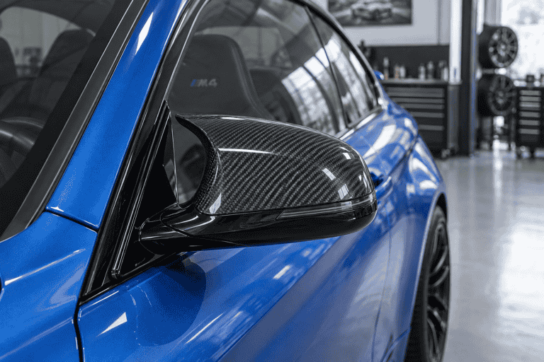 Close-up concept of a carbon fiber exterior mirror cap on a blue BMW M4