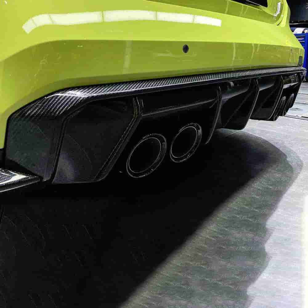 Rear bumper detail of a green car showing a diffuser and exhaust outlets.