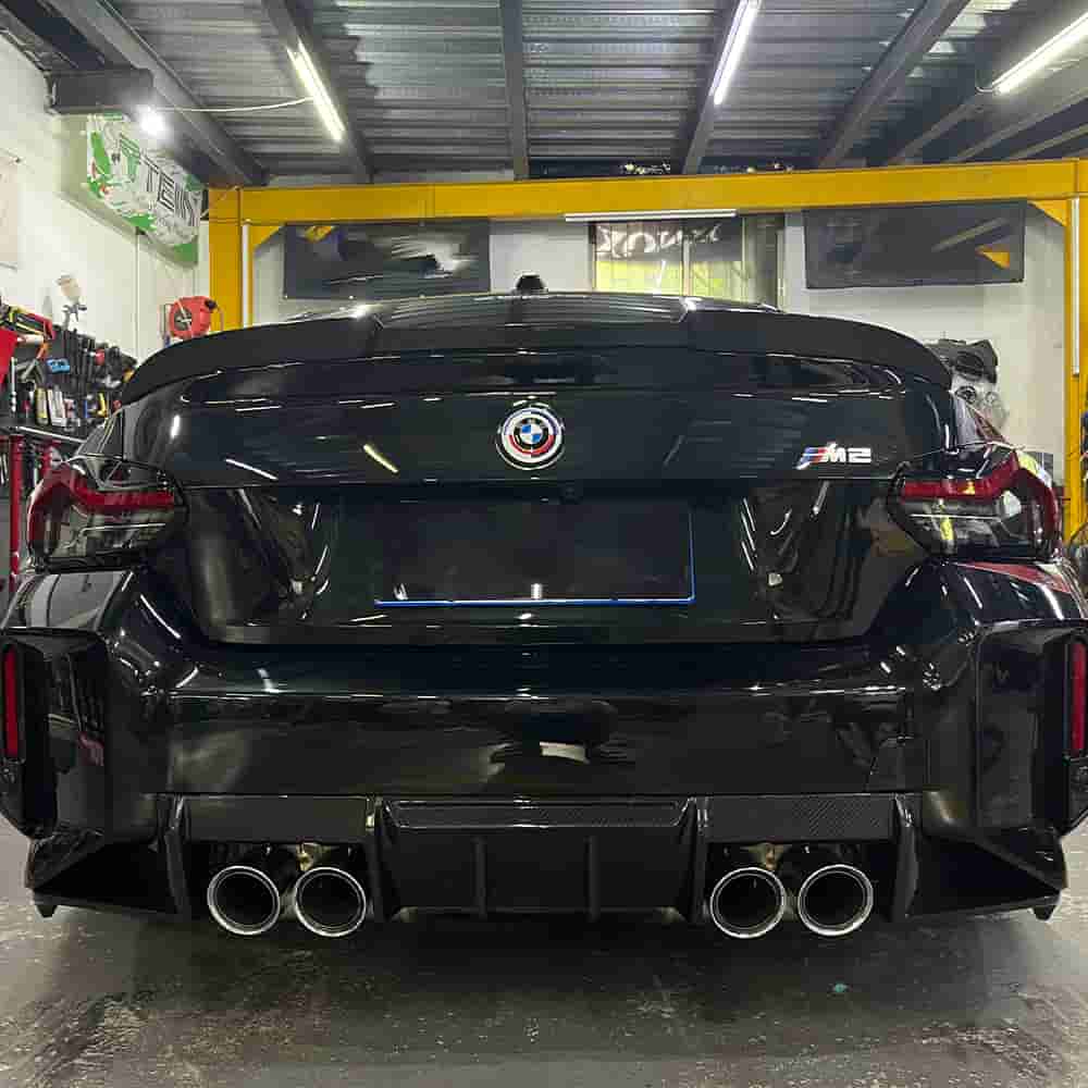Rear view of a dark BMW in a workshop.
