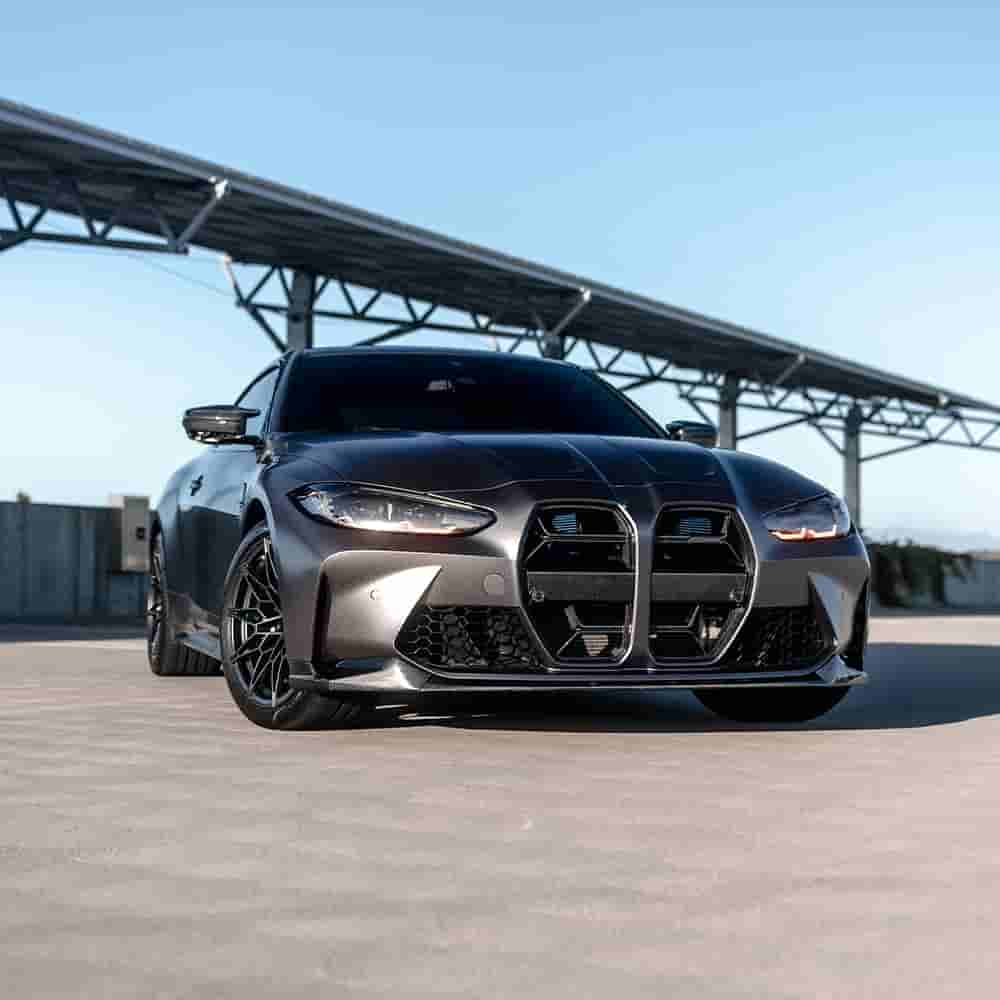 Front-quarter view of a dark BMW at a track-side location.