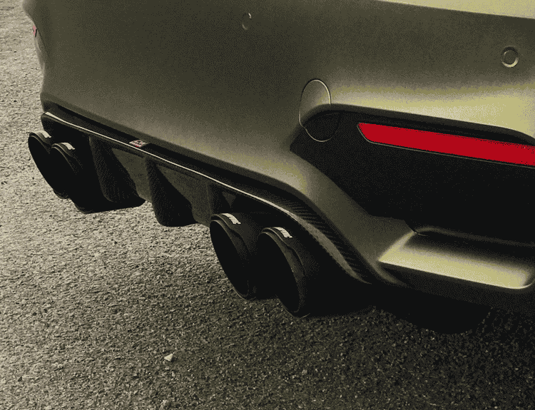 Close rear-bumper view of a vehicle with diffuser fins and exhaust tips.