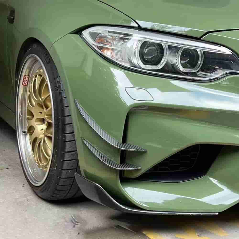 Bumper corner of a green BMW with stacked styling fins.