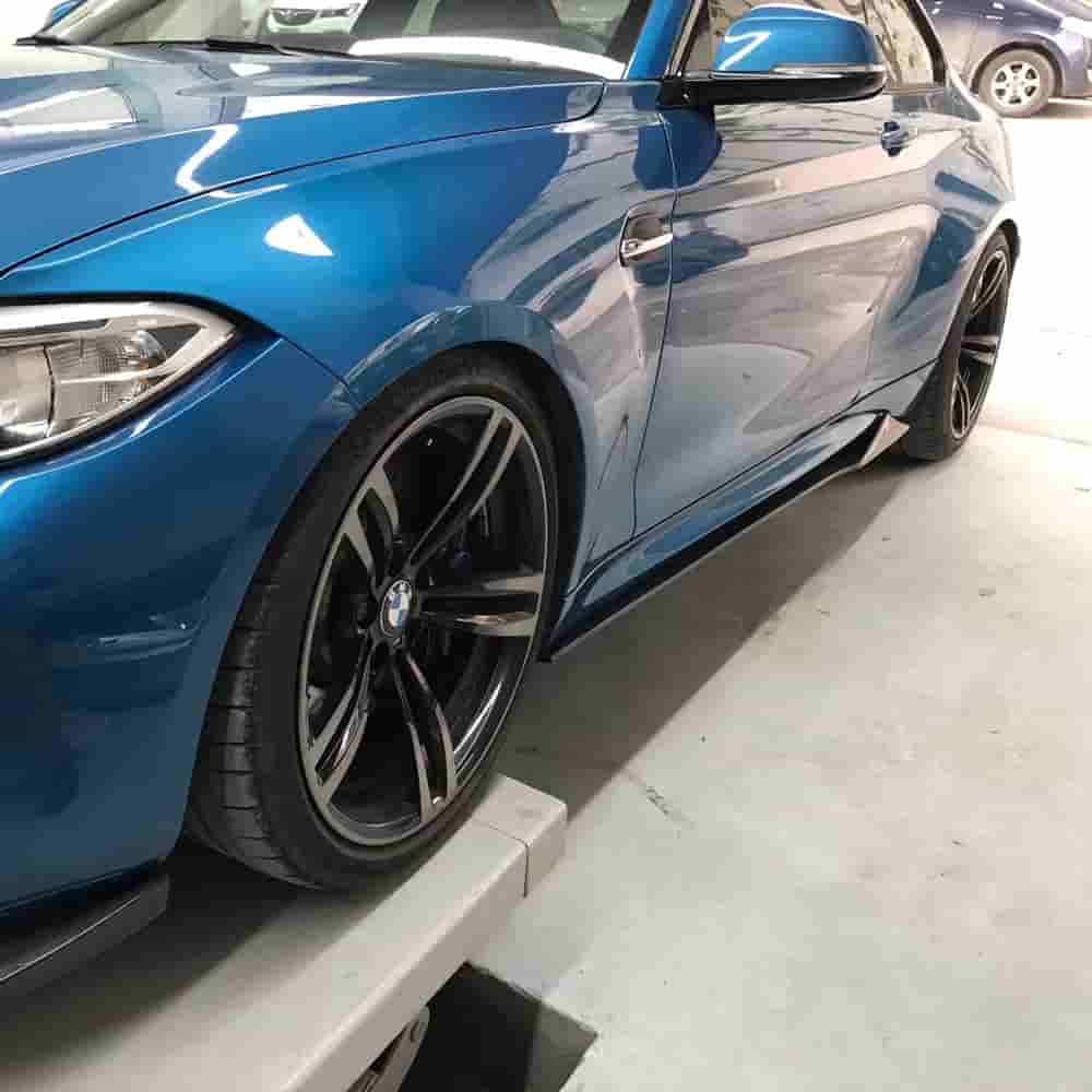 Front-side view of a blue BMW with side skirt styling.