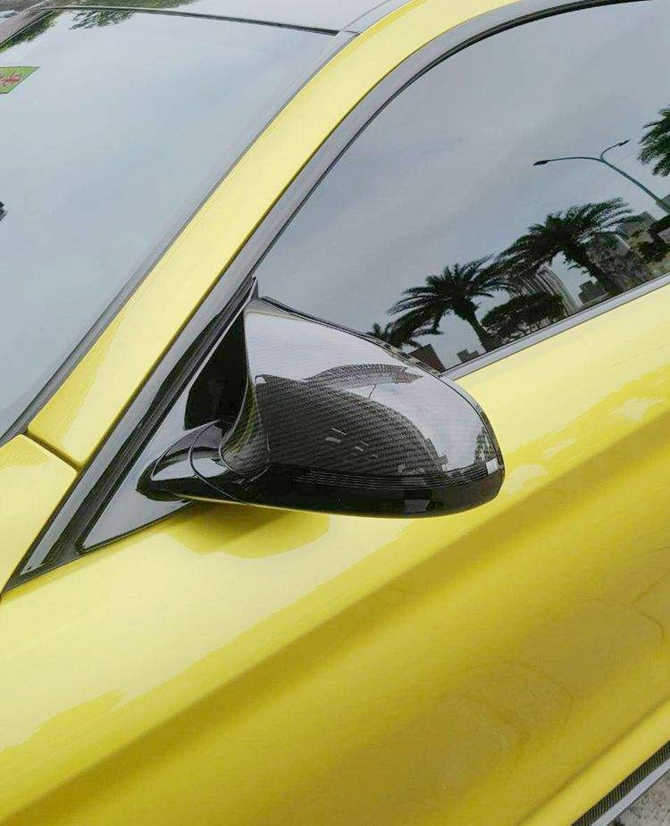 Close view of a mirror cap installed on a yellow vehicle.