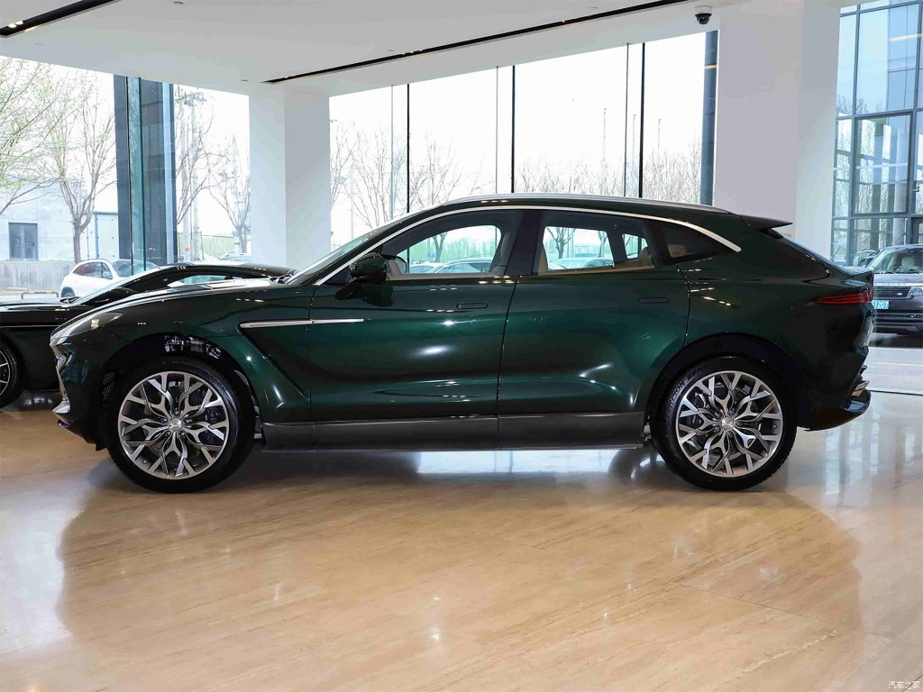 Side view of a dark green SUV with lower side styling.