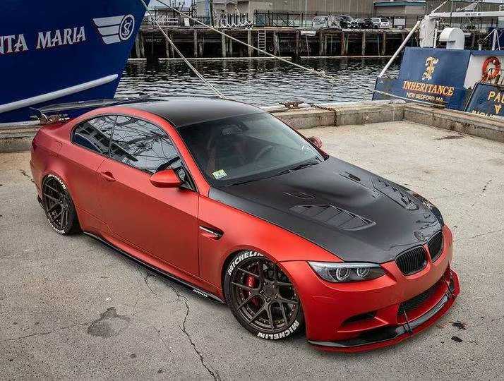 High front-quarter view of a red BMW with a dark hood.