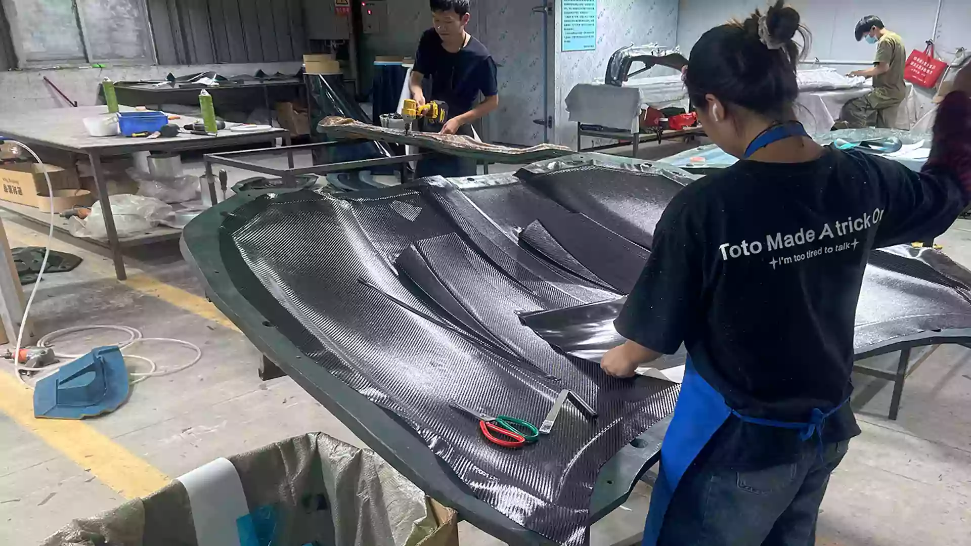 Worker laying carbon fiber material for automotive parts at CCF factory